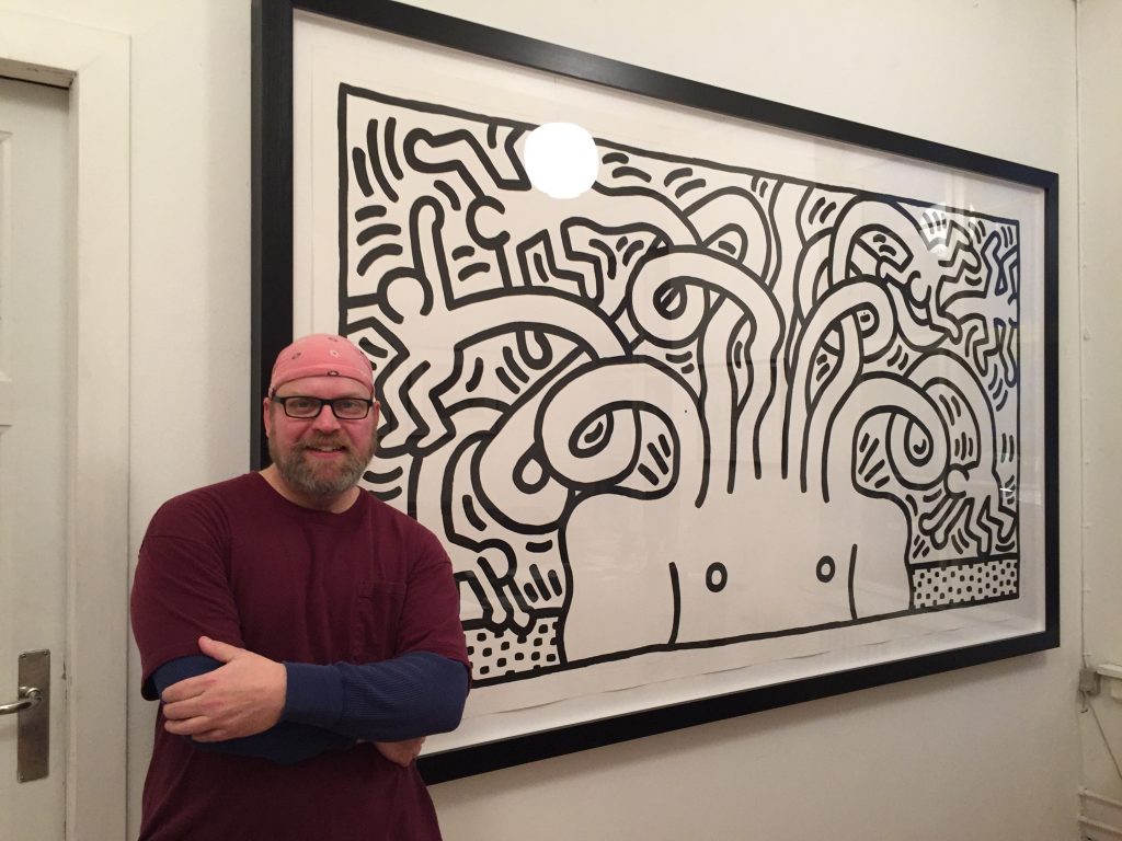 Jon Lybrook at Nils Borch Jensen Studios in 2018 in front of a large Keith Haring print.